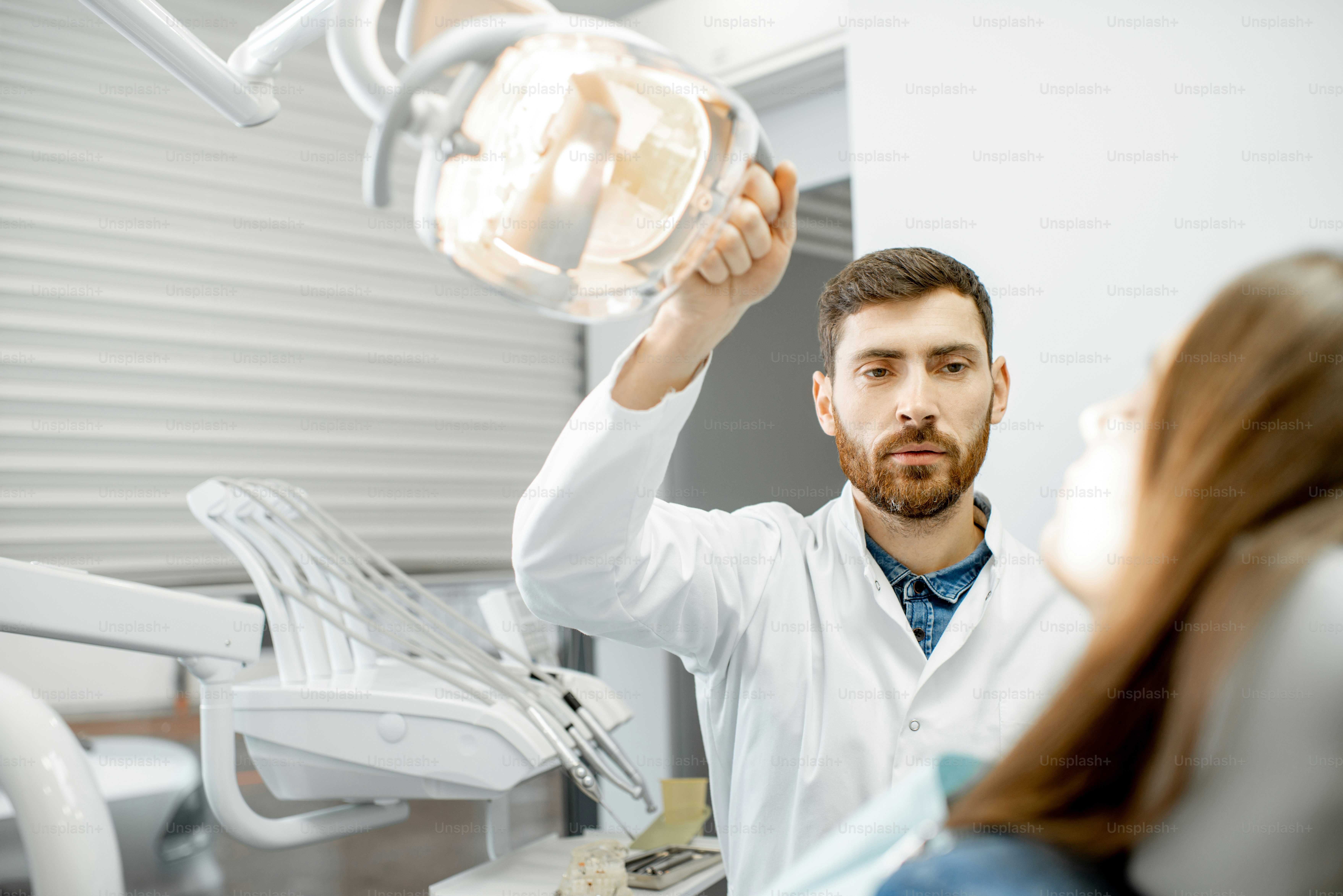 Dentist preparing for the medical examination with young woman patient in the dental office
