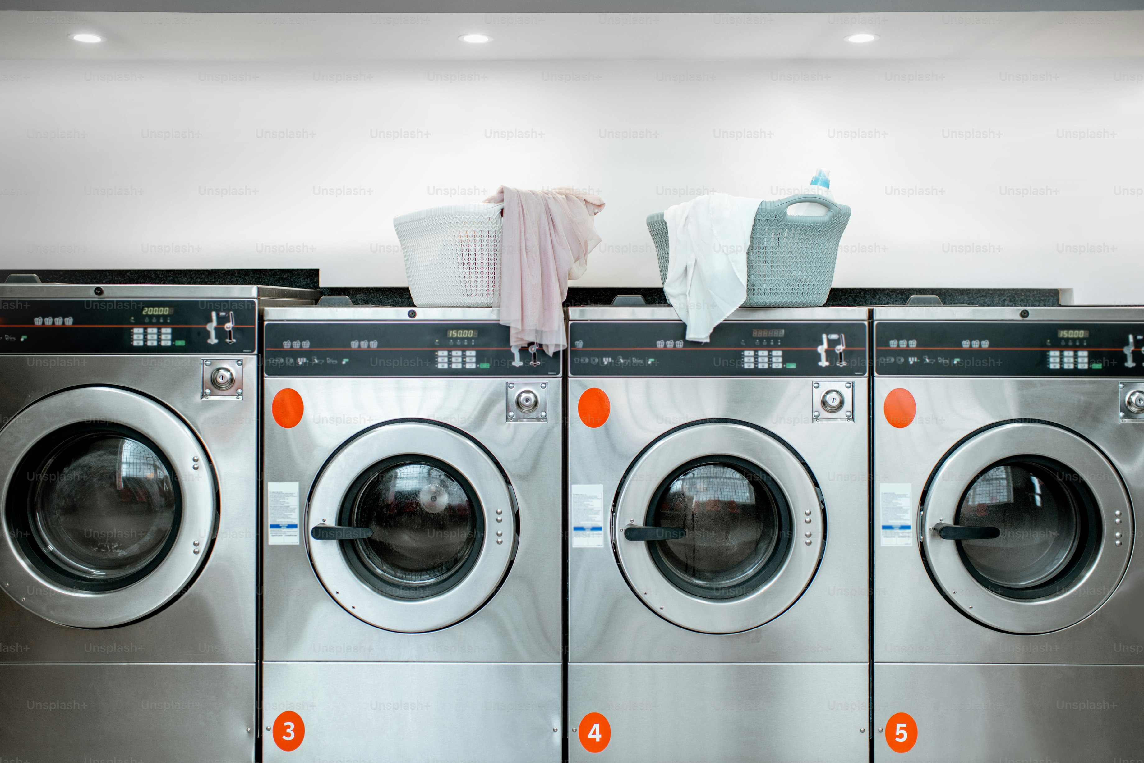 Professional washing machines with baskets full of clothes at the self-service laundry