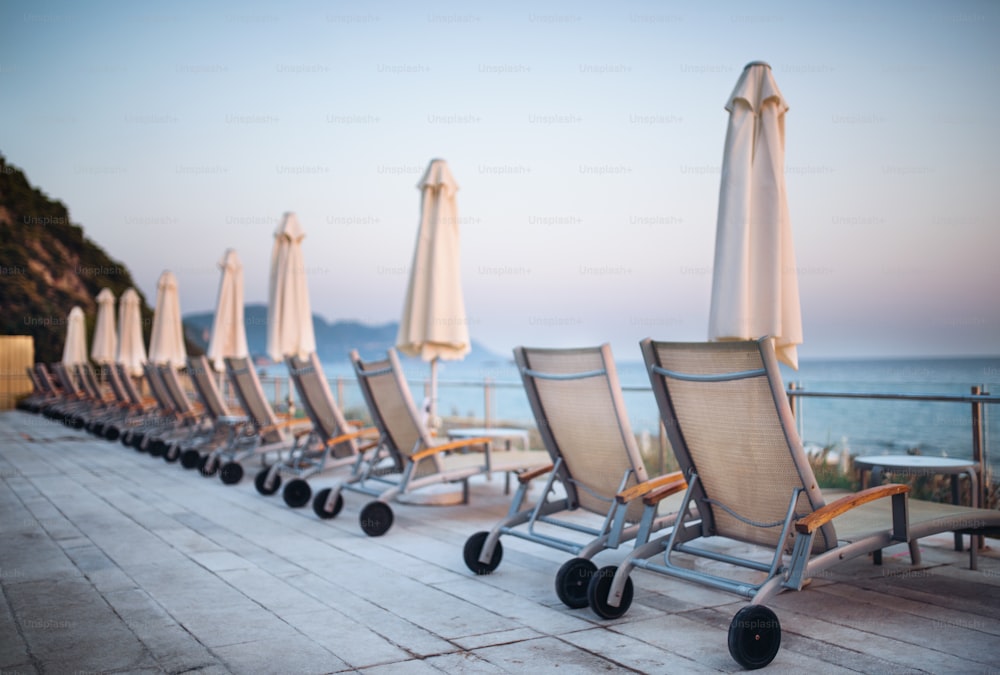 Liegestühle und Sonnenschirme in einer Reihe am tropischen Strand, Sommerurlaubskonzept.