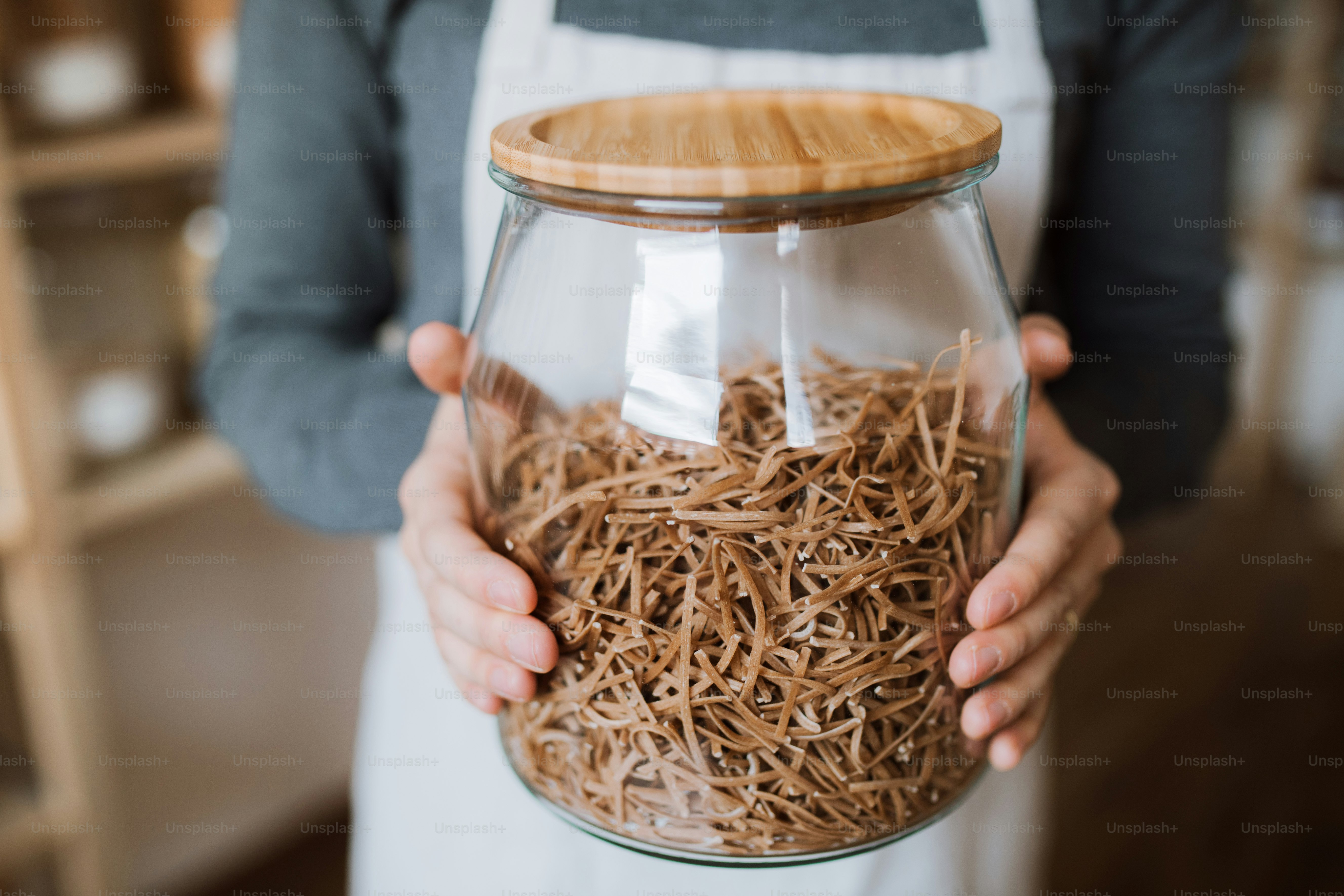 Un barile di una commessa in un negozio a rifiuti zero, con in mano un barattolo con la spesa. Un primo piano.