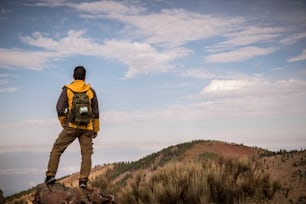 トレッキングアドベンチャーの孤独な男は、バックパックで山でのアクティビティを発見します-ハイカーは風景を見て、野生の未発見の自然を楽しんでいます-代替休暇のための美しい環境