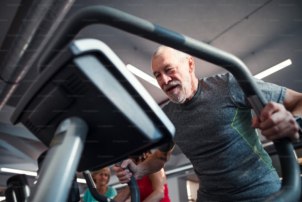 Un hombre mayor haciendo ejercicio de fuerza en el gimnasio. Un espacio de copia.