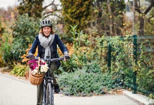 An active senior woman with helmet and electrobike cycling outdoors in town. Copy space.