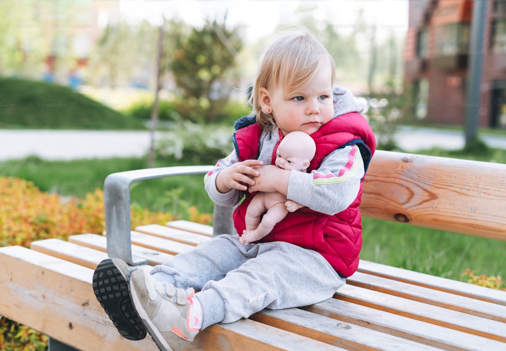 Cute funny baby girl sad child walking at street sitting on bench