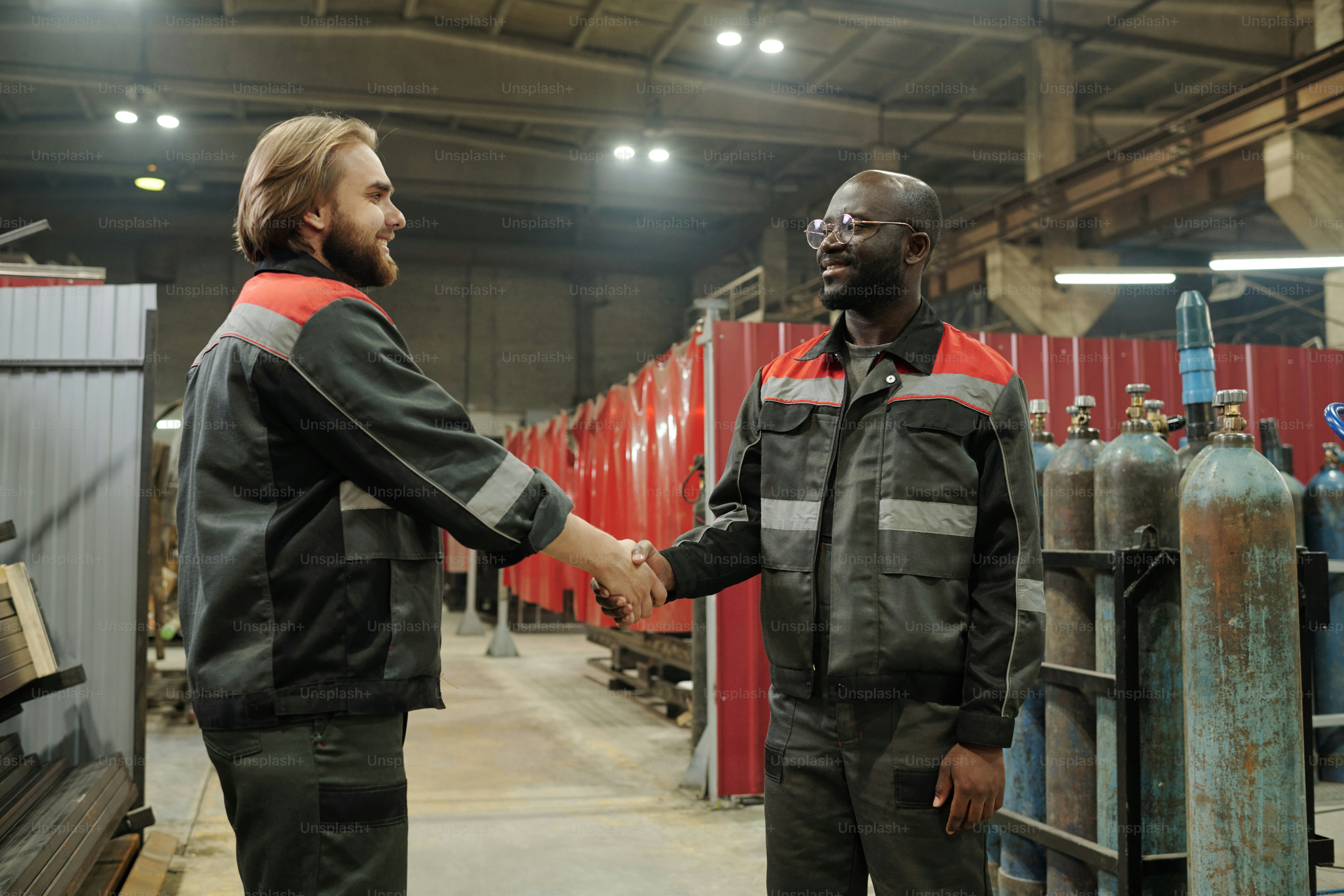 Two young confident male engineers shaking hands after negotiating and ...