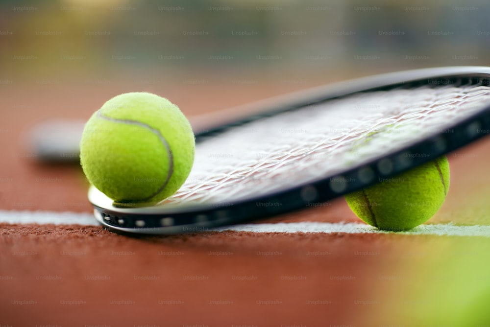 Deporte. Pelotas De Tenis Y Raqueta En La Cancha. Primer plano del equipo para deportes como la raqueta de tenis y la pelota amarilla que yace en la cancha abierta. Alta calidad
