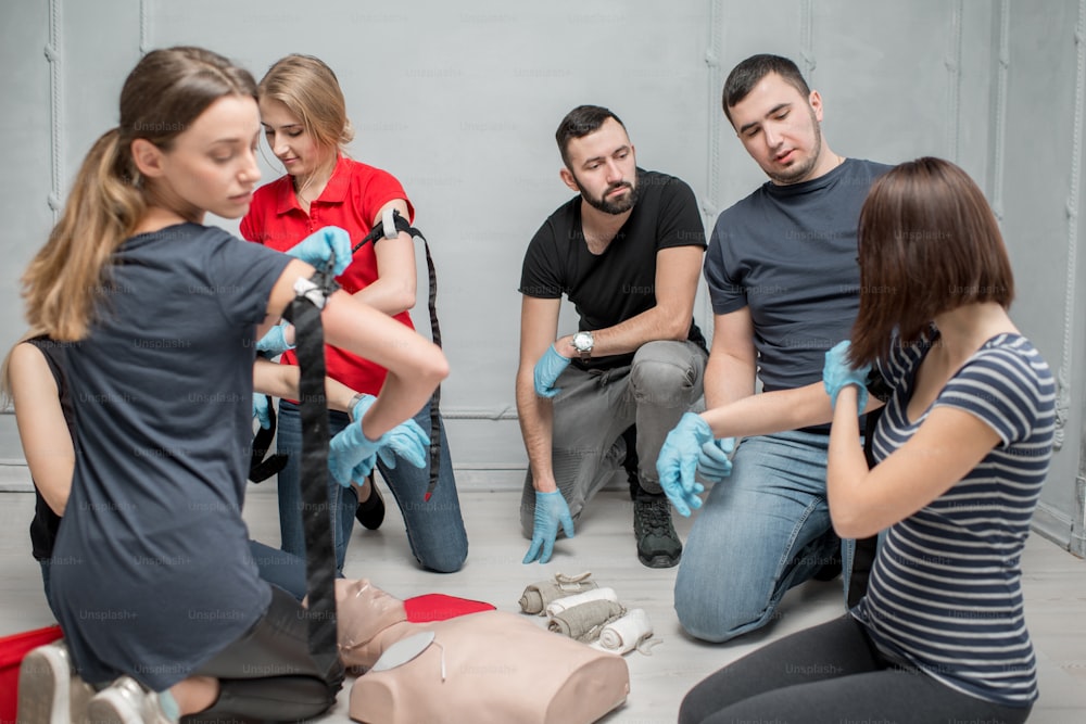 屋内での応急処置訓練中に出血を防ぐために止血帯を装着することを学ぶ人々のグループ