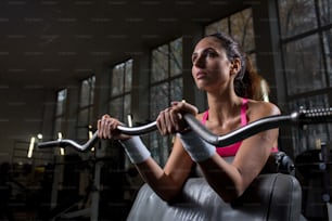Pretty sportswoman weightlifting in contemporary sports club during workout