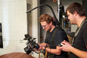 Deux vidéastes ou caméraman et son assistant se préparent pour le tournage et consultent sur le réglage de l’équipement