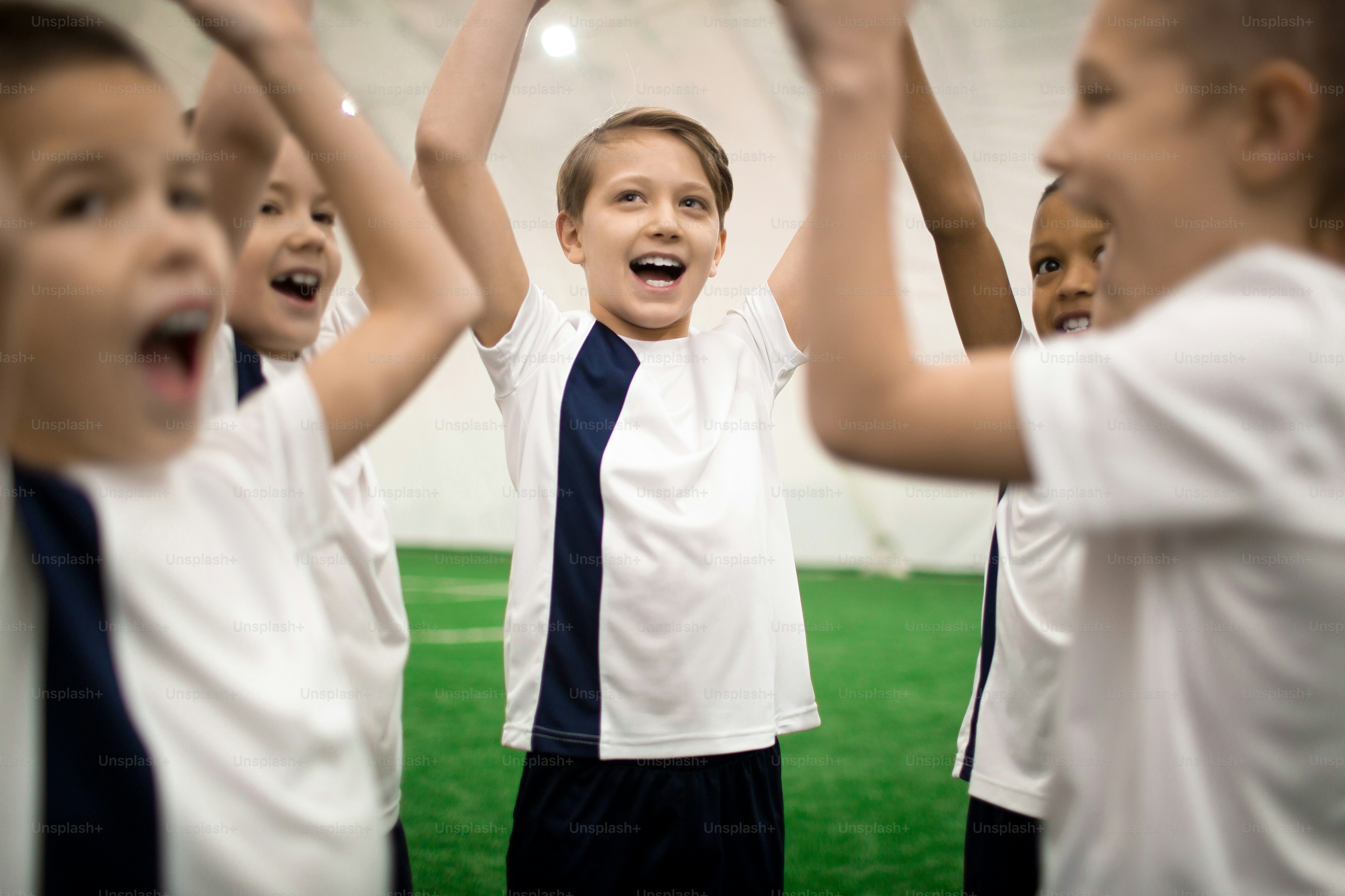 Ecstatic participants of football games in uniform raising their hands and shouting