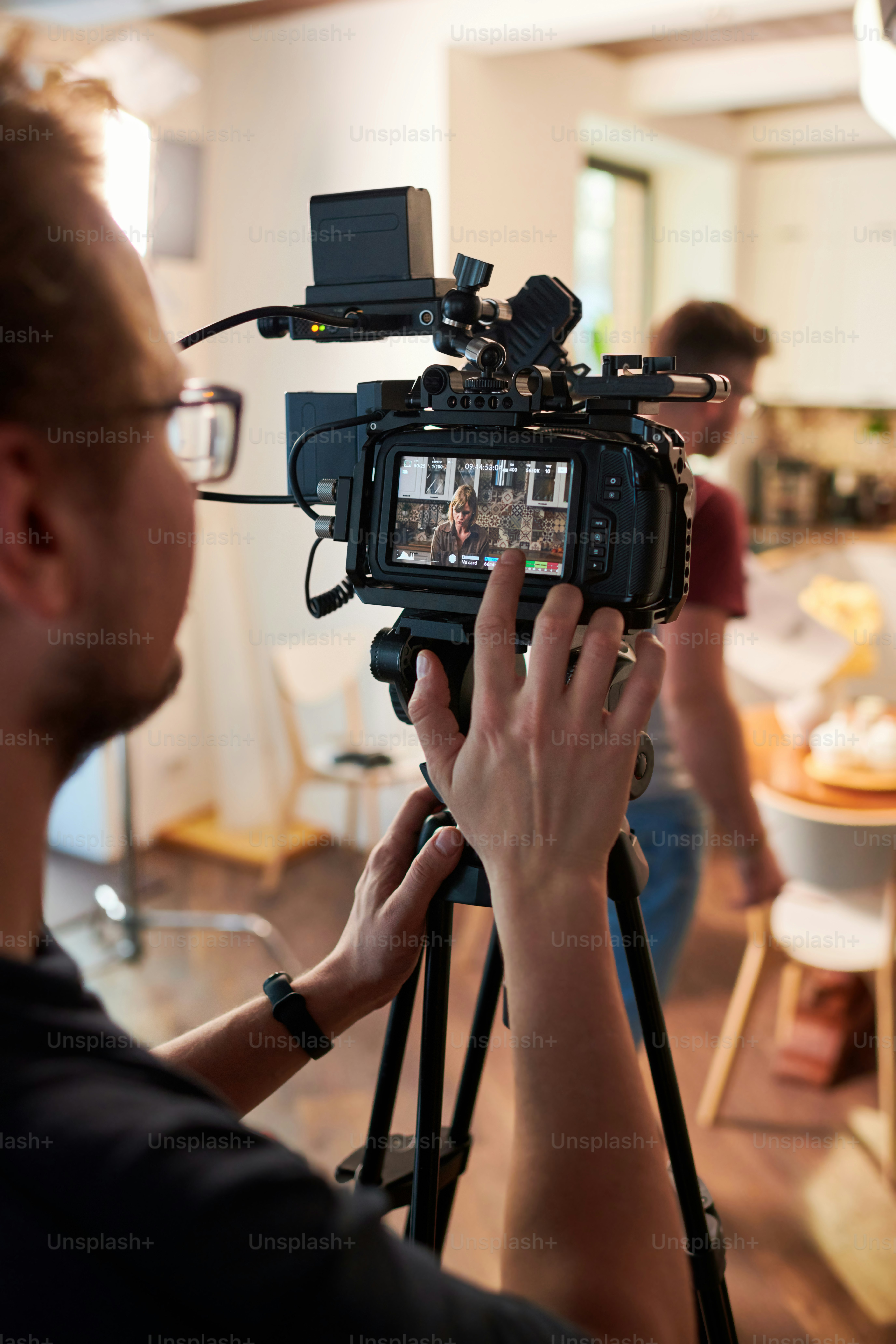 Contemeporary videographer or cameraman adjusting video camera options while standing in front of place prepared for shooting