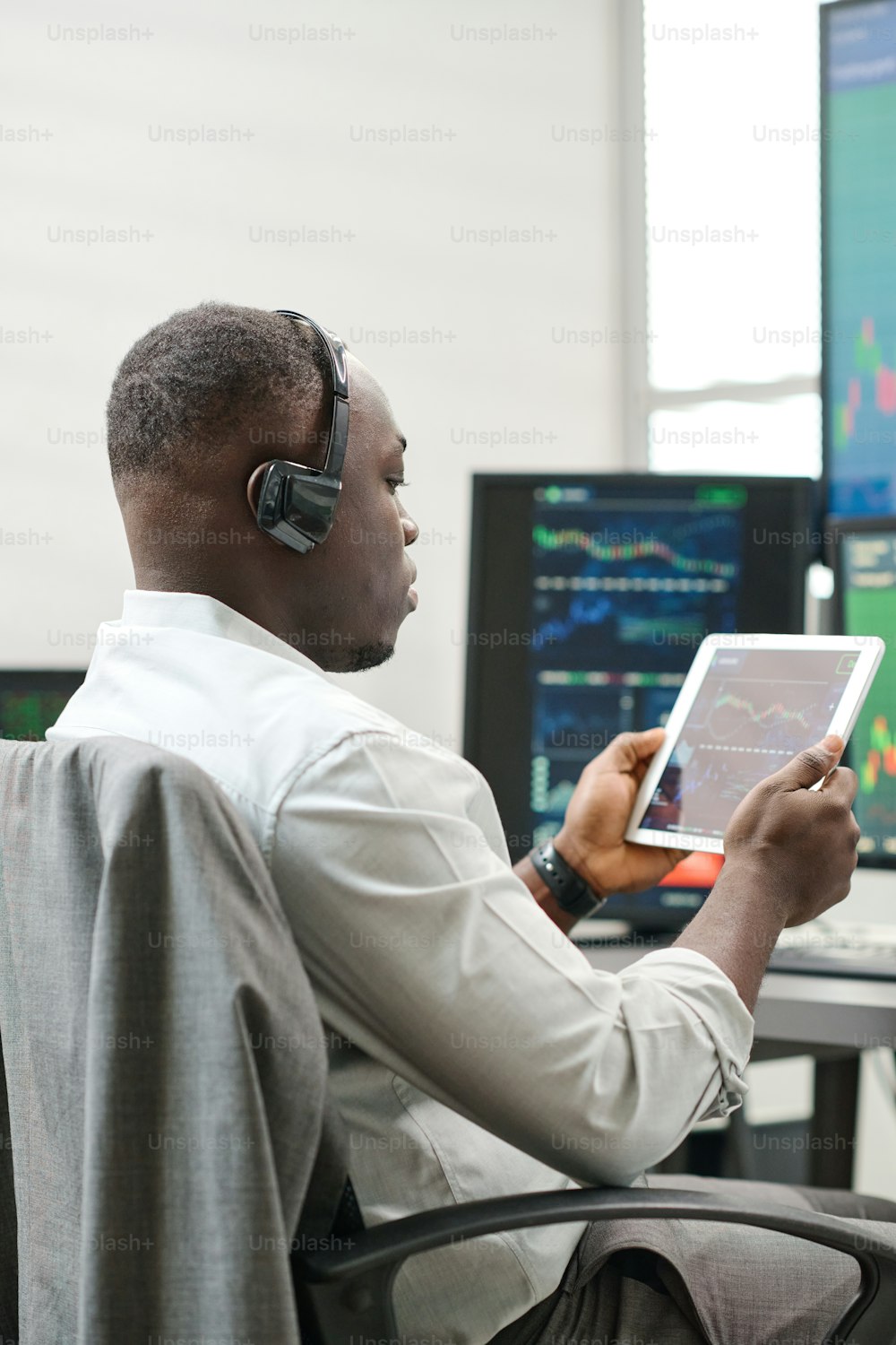 African American man holding digital tablet working with stock trading stats watching charts and graphs of currency