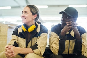 Two workers in uniform sitting and resting during break at warehouse