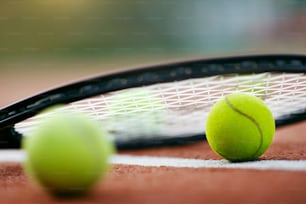 スポーツ。コート上のテニスボールとラケット。オープンコートに横たわるテニスラケットや黄色いボールなどのスポーツ用具の接写。高品質