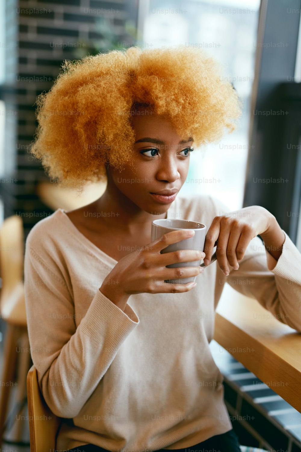 창문 근처 카페에서 커피 음료를 마시는 아름다운 소녀. 카페에서 뜨거운 음료의 cu0p와 함께 캐주얼 옷을 입은 젊은 웃는 아프리카 여성의 초상화. 고해상도