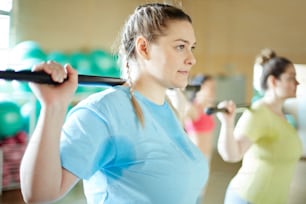 Giovani donne sudate con barre da ginnastica che fanno esercizi durante l'allenamento