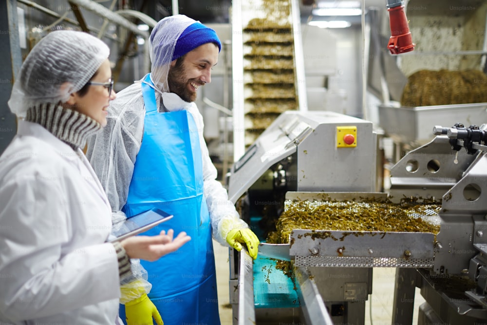 Deux travailleurs d’une usine de fruits de mer discutent en produisant une salade d’algues