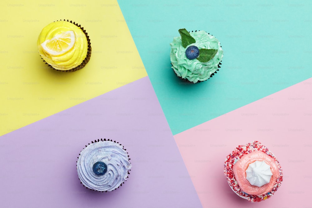 Cupcakes Desserts On Colorful Background. Cakes With Different Colors Cream And Toppings. High Resolution