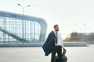 Voyage d’homme d’affaires en voyage d’affaires. Bel homme en costume avec valise allant à l’aéroport. Haute résolution