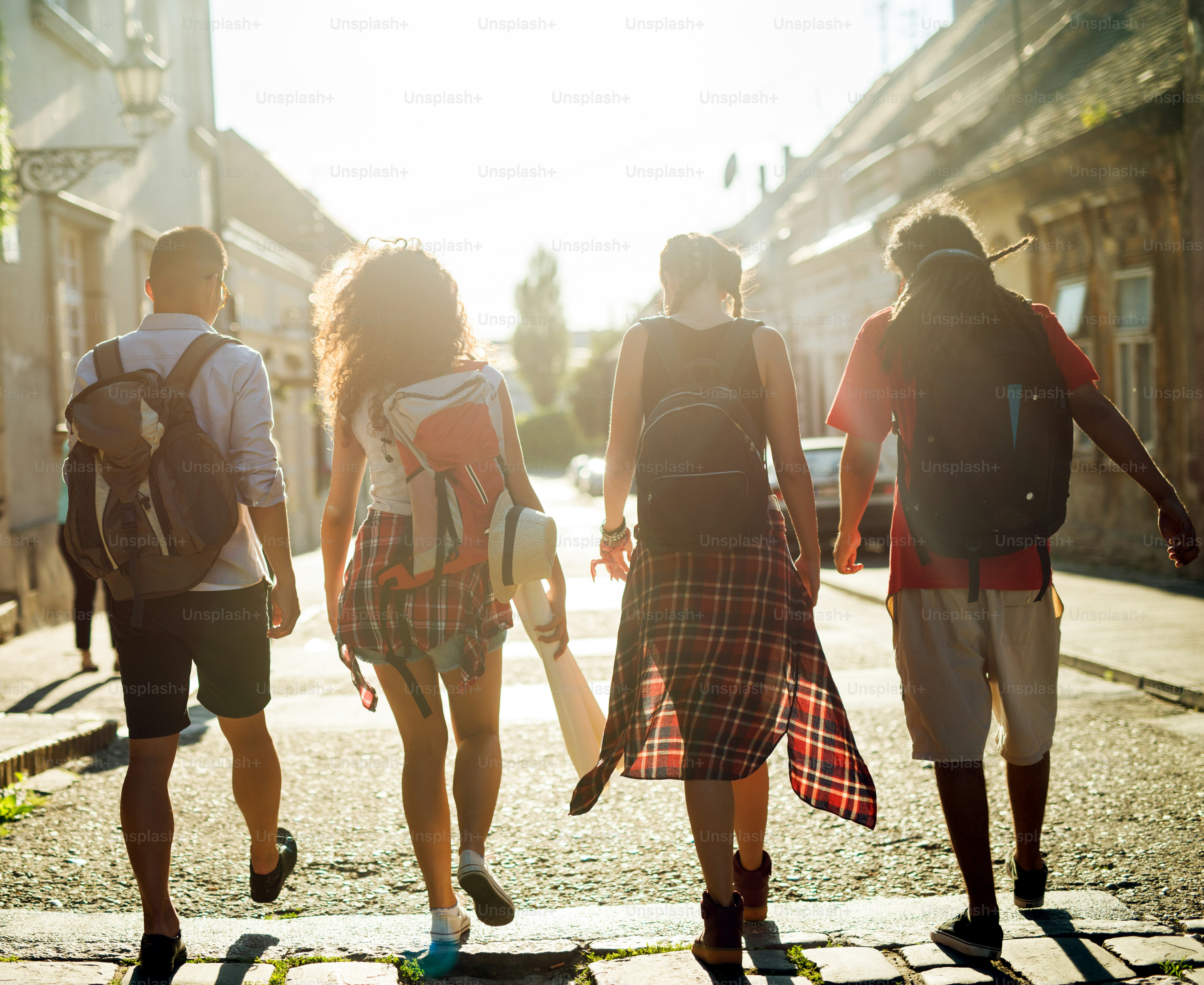 Rear view of four touristic friends walking down the street.
