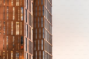 Fragmento de uma fachada de arranha-céu moderna feita de vidro e concreto com várias janelas iluminadas pelo sol e com uma área vazia de espaço de cópia à direita para sua publicidade ou mensagens de texto