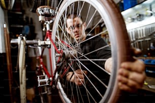 Joven profesional ajustando los cables de las ruedas de la bicicleta.