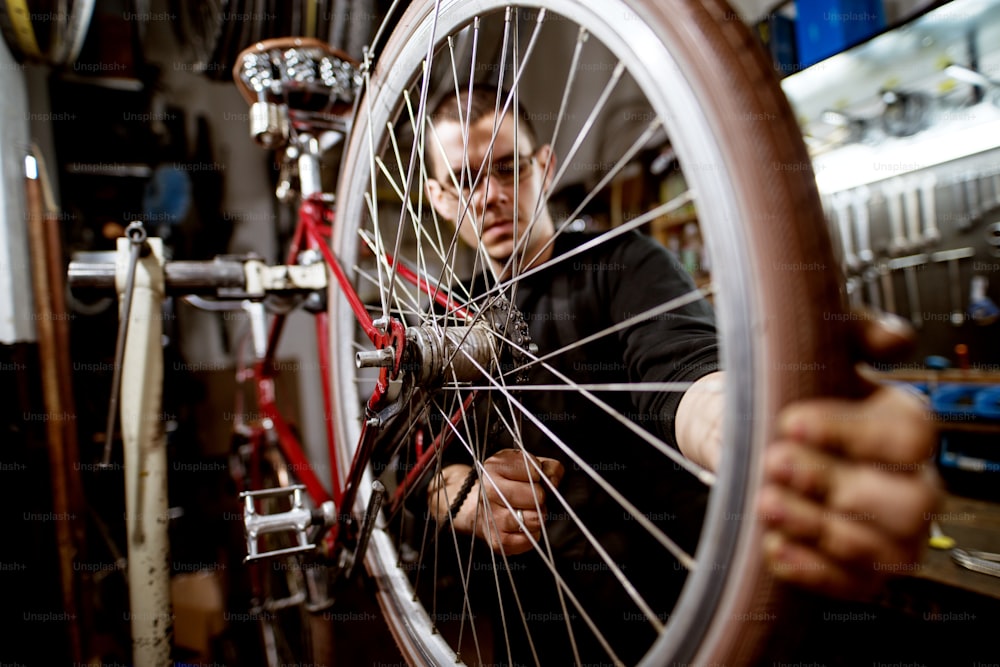 Professional young man adjusting bicycle wheel wires.