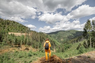 Person in orangefarbenem Sportanzug und Rucksack genießt einen herrlichen Blick auf die Berge und reist im Sommer in der Natur