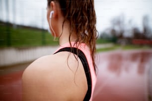 Close up rear view of athletic woman's shoulder while standing on running track.