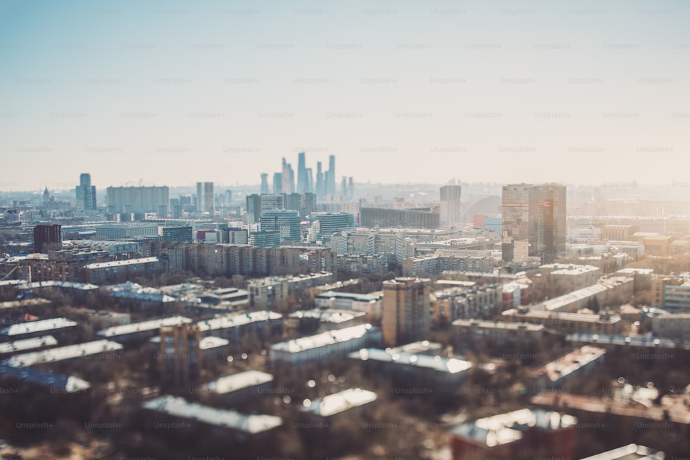 True tilt-shift view of autumn or spring cityscape with skyscrapers and residential houses, with focus on the middle zone of the image; background and foreground are blurred and have strong bokeh