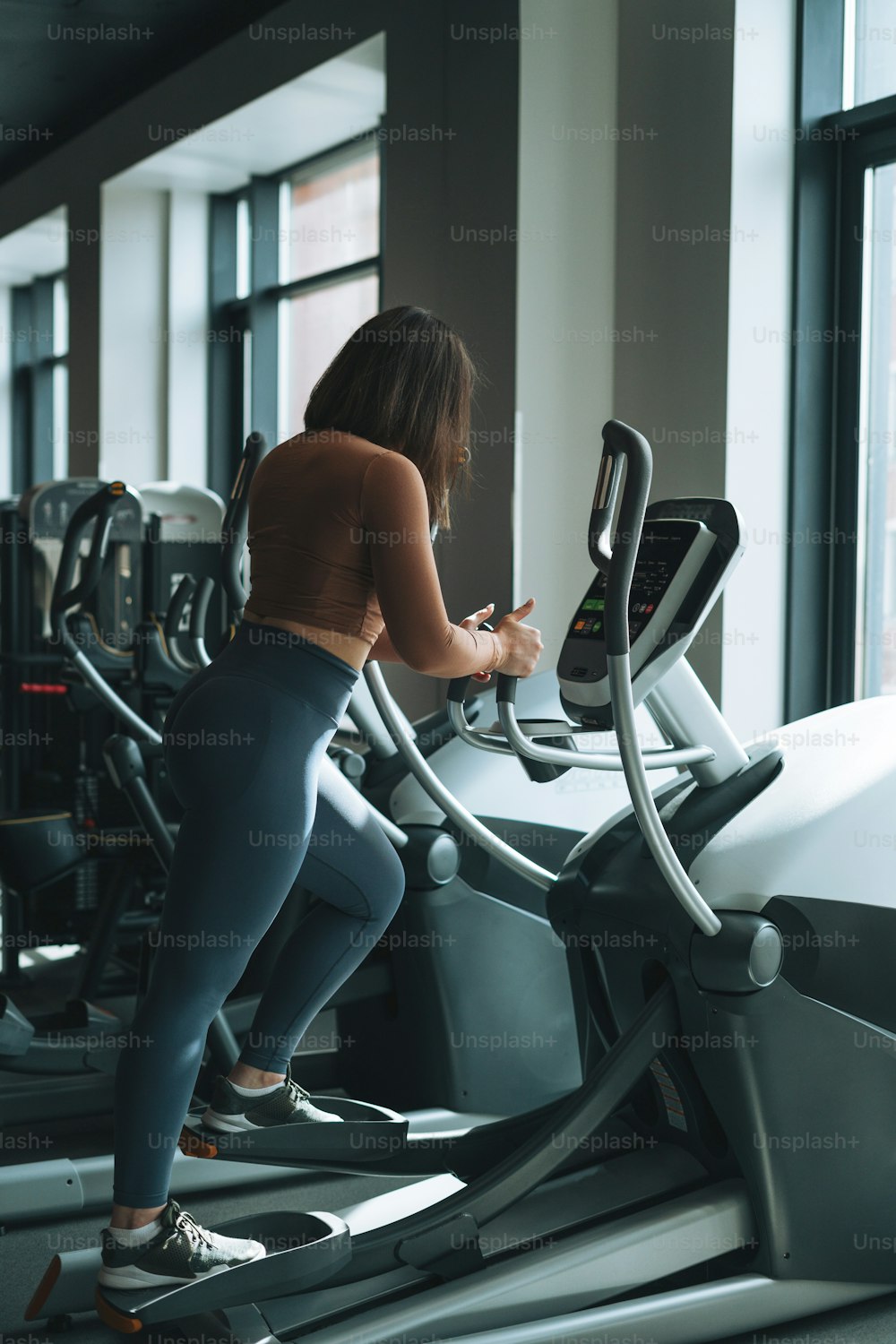 Young brunette woman training for cardio equipment at fitness club gym