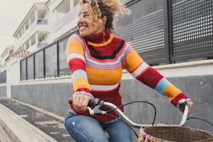 Mujer joven madura feliz montando en bicicleta y sonriendo disfrutando de una actividad de ocio saludable activa al aire libre. Ambiente verde y medio ambiente medio de transporte con mujeres que usan la bicicleta