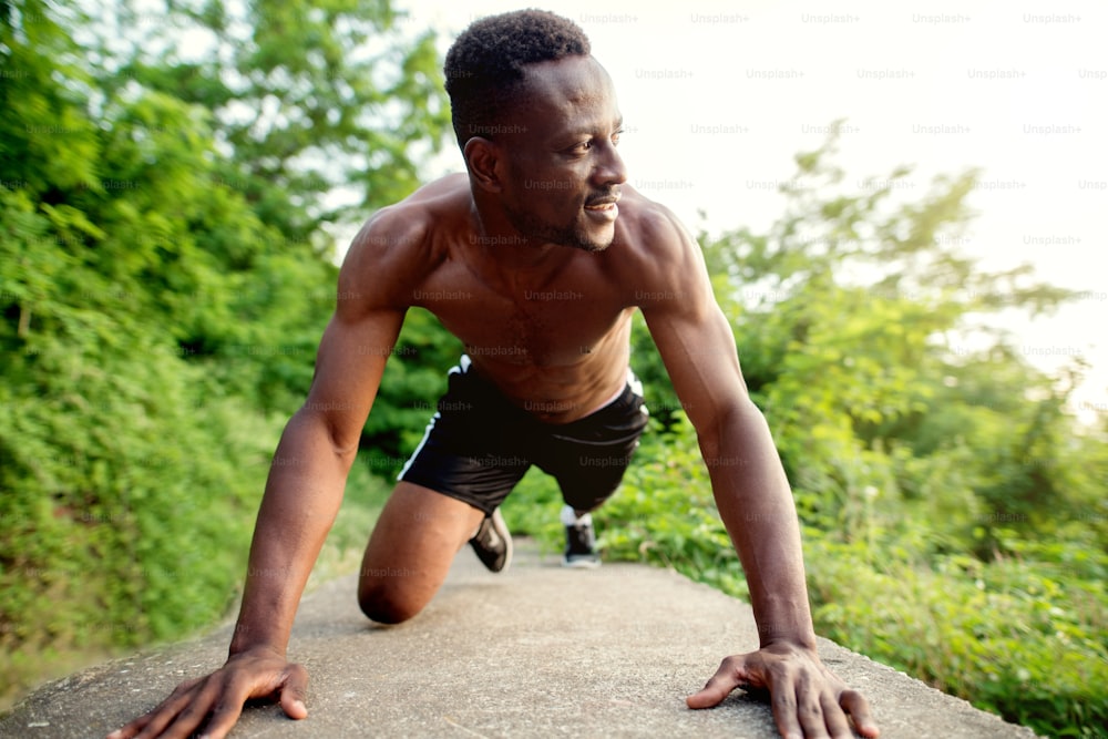 Afro-americano fitness homem bonito treinando. Correndo contra o sol da manhã.