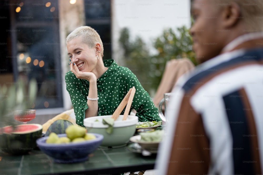 Multiracial couple having dinner at backyard of their country house. Idea of healthy eating and modern lifestyle. Black man and european woman having heart-to-heart conversation enjoying time together