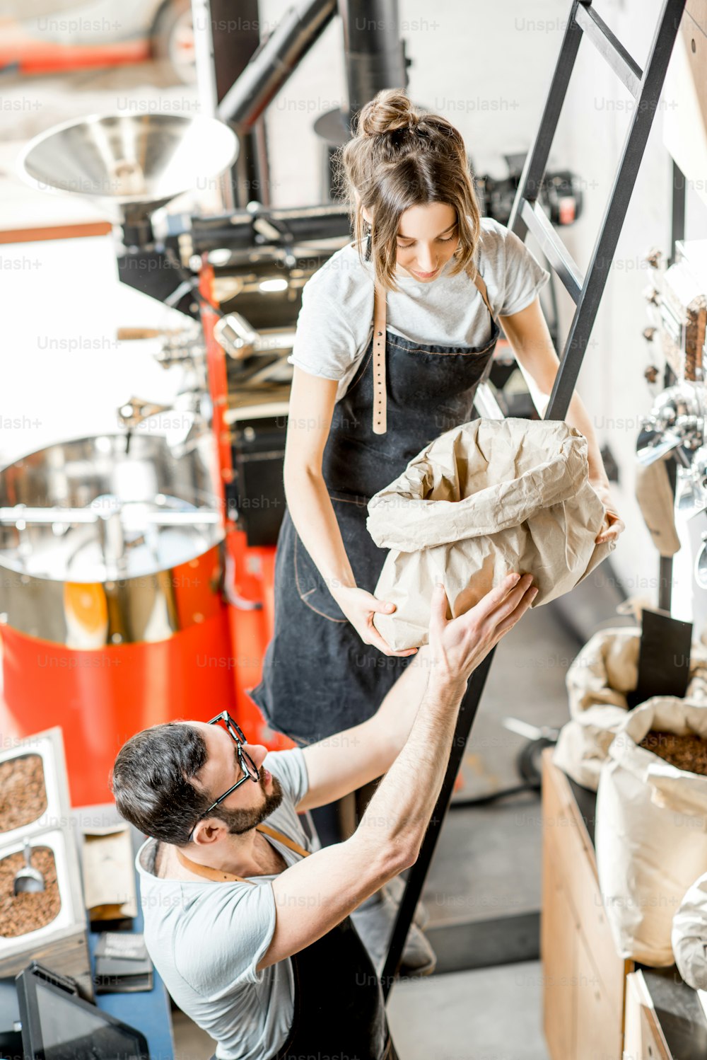 Two sales persons working with coffee in the coffee shop with roaster machine on the background