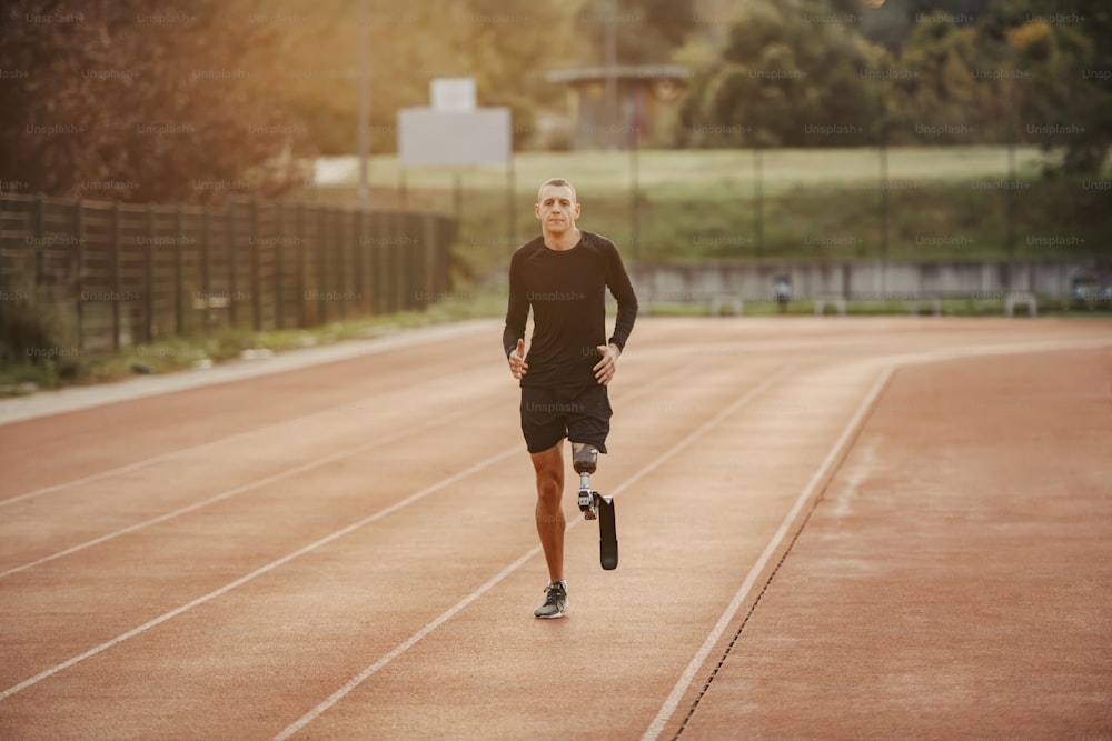 Un corredor discapacitado sano con pierna artificial corriendo en la pista de atletismo del estadio.