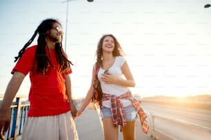 Multiracial couple walking down the street smiling. Coming back from music festival early in the morning.