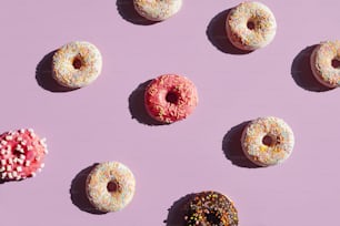 Bunte Donuts auf lila Hintergrund im Sommer. Nahaufnahme von Süßigkeiten mit Streuseln und Glasur unter Sonnenlicht. Hohe Auflösung