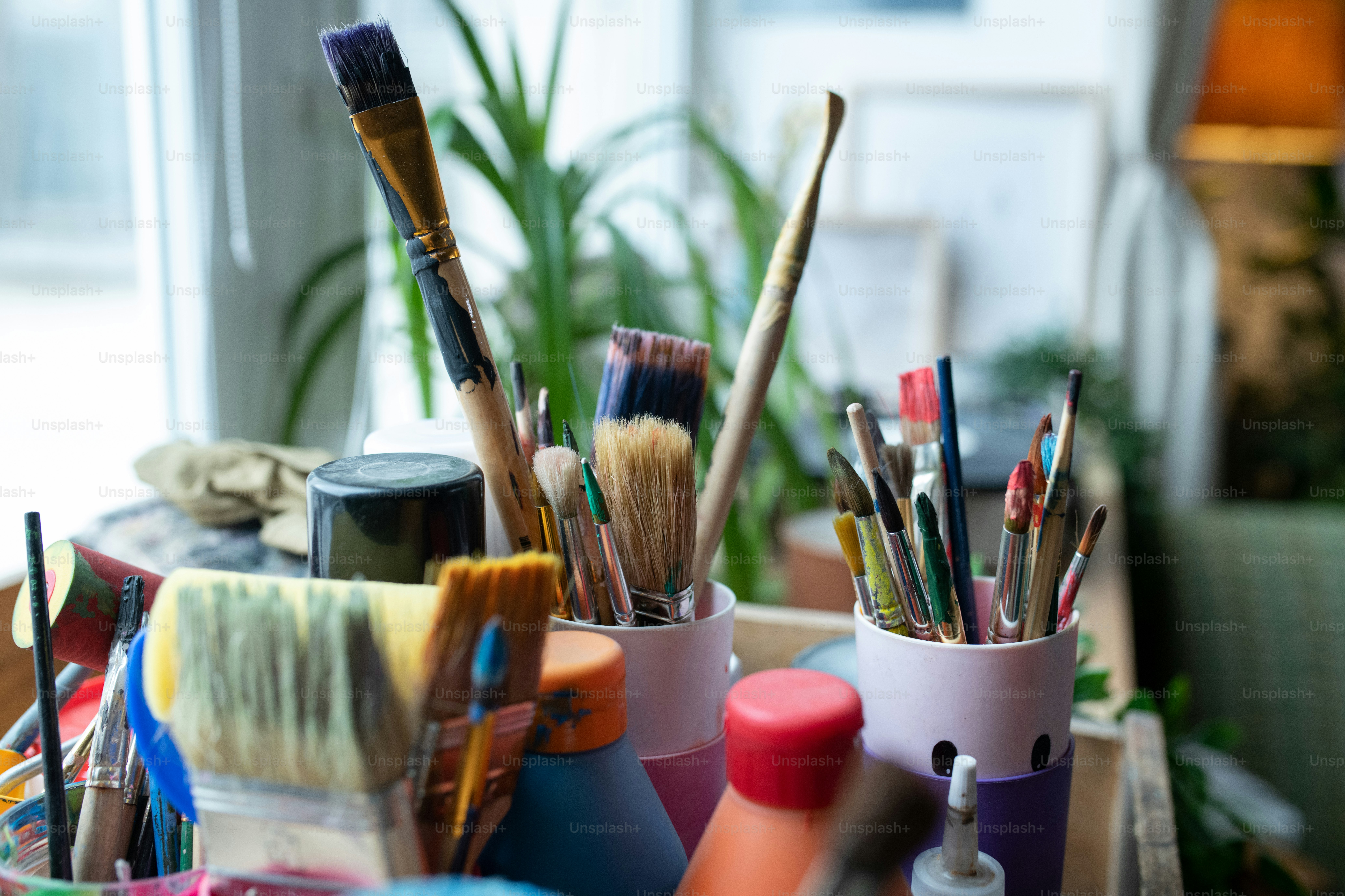 Close-up no people still life shot of various paintbrushes and liquids in bottles on windowsil in daylight