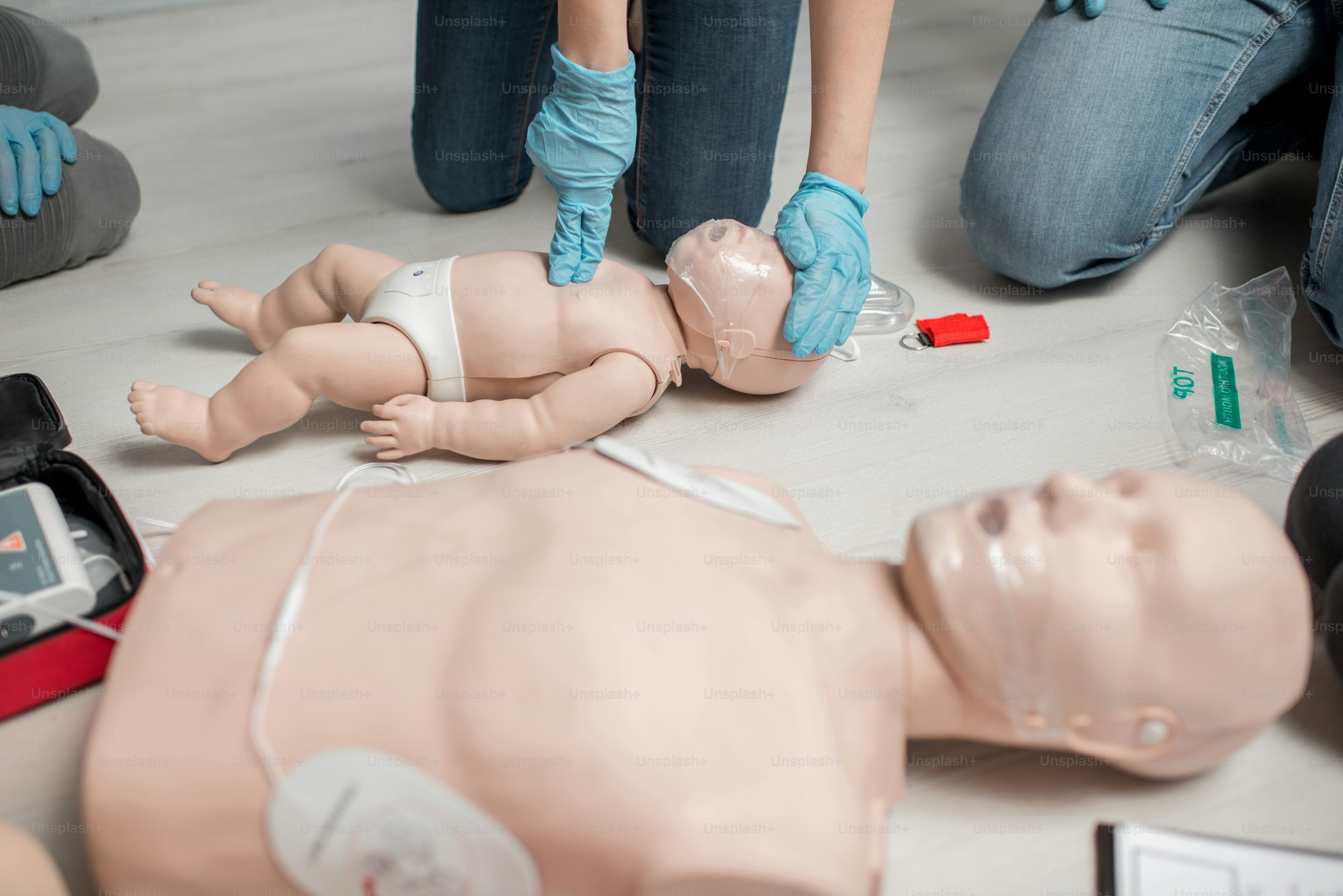 Instructor showing how to make chest compressions on a baby dummy during the first aid training indoors