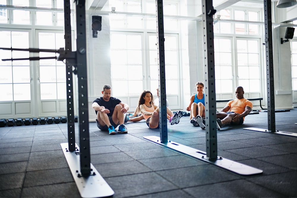 Vielfältige Gruppe von Freunden, die Crunches machen, während sie zusammen auf dem Boden eines Fitnessstudios trainieren