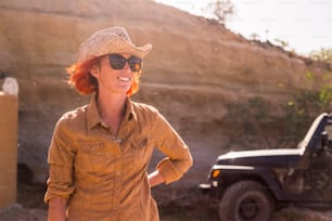 beautiful happy caucasian female working outdoor in a country farm near mountains. warm climate weather like far west. off road car in the background for alternative life concept in feeling with the nature and no stress