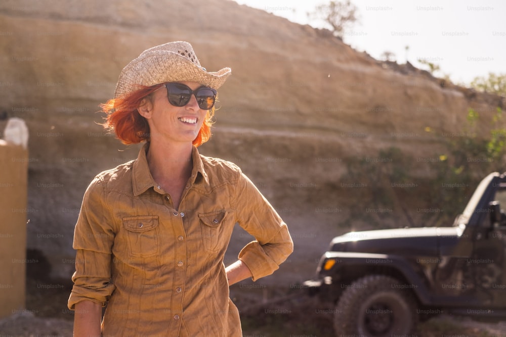 beautiful happy caucasian female working outdoor in a country farm near mountains. warm climate weather like far west. off road car in the background for alternative life concept in feeling with the nature and no stress