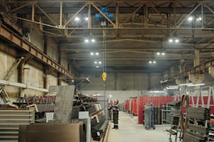 Interior of spacious factory workshop where male engineer adjusting industrial machine or other construction equipment