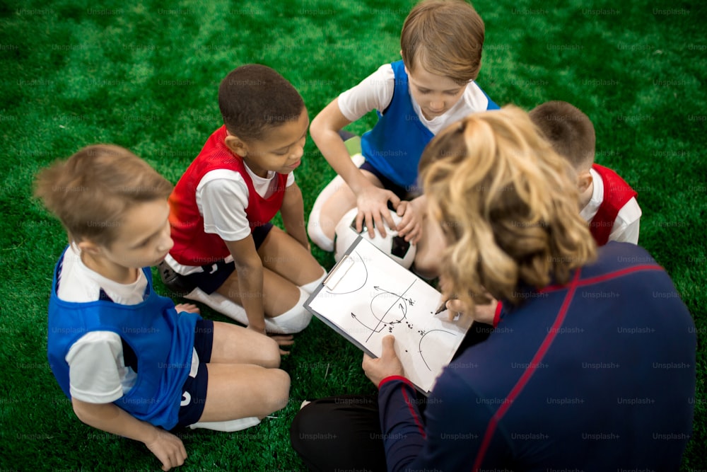 Esquema de dibujo del instructor de fútbol de moverse durante el partido de fútbol o entrenamiento y explicárselo a un grupo de niños