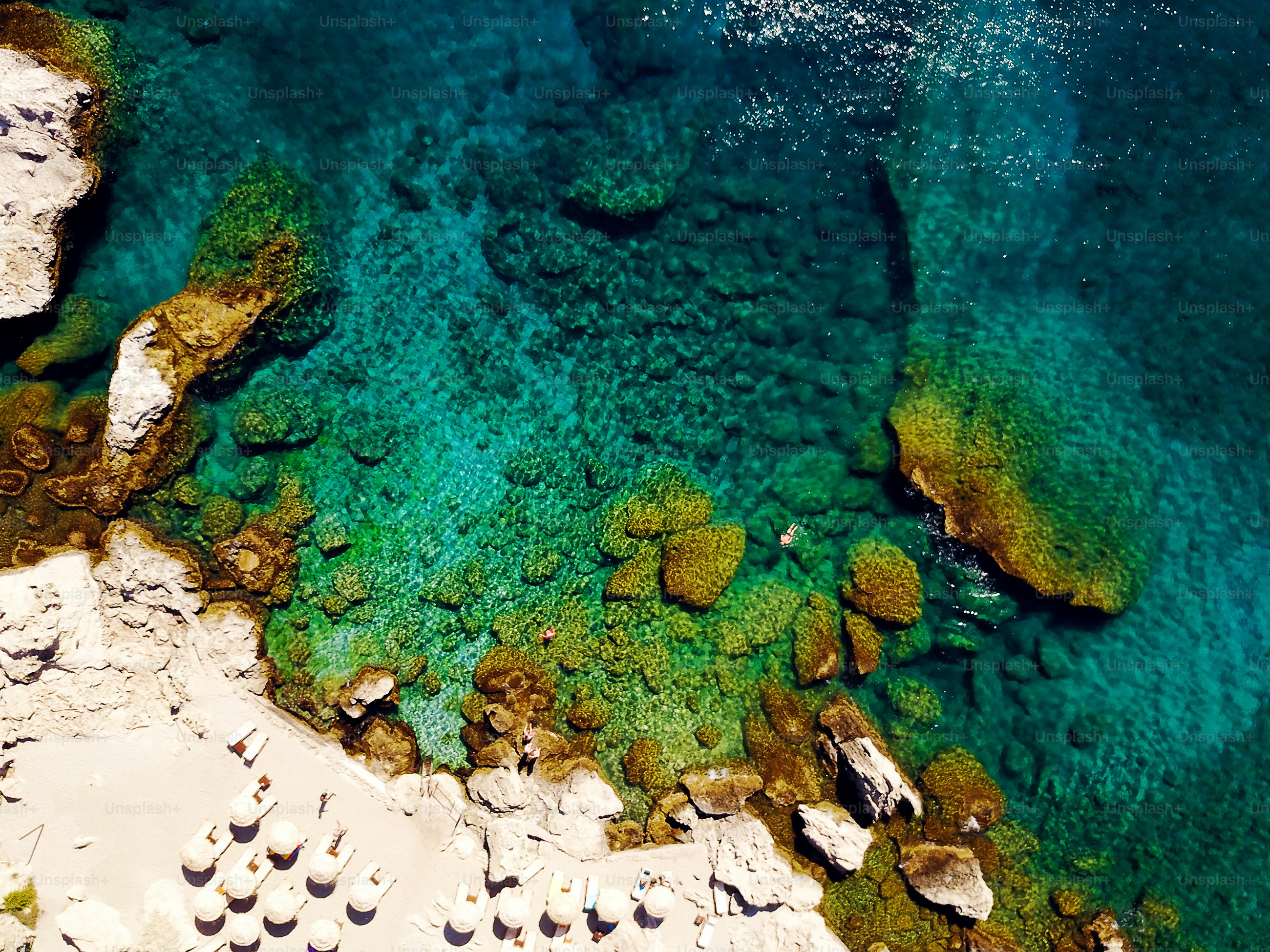 Vue de dessus de la plage avec des touristes nageant dans une belle eau de mer claire.