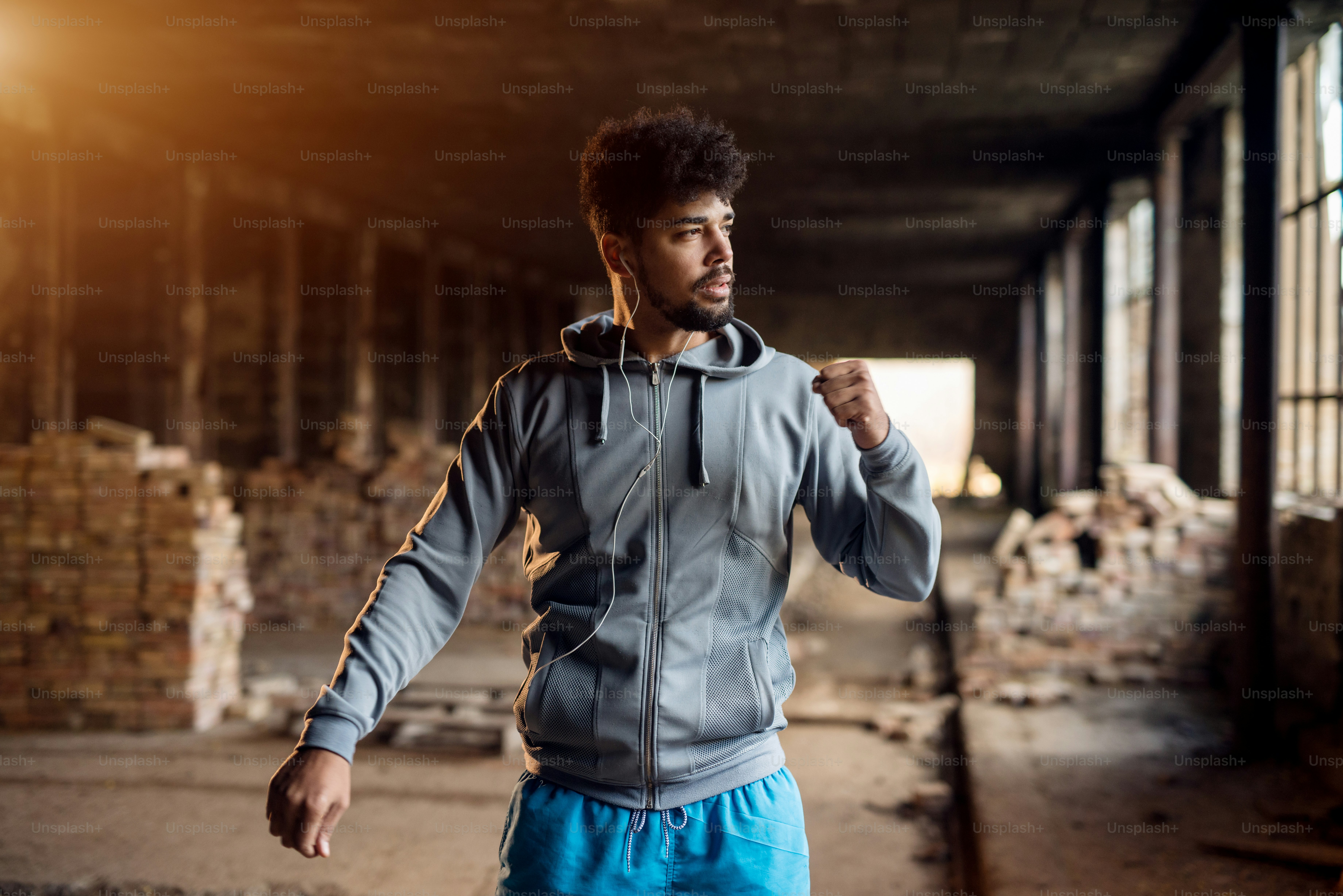 Close up portrait of active afro-american young attractive athletic man doing full hand stretching workout inside of the abandoned place.