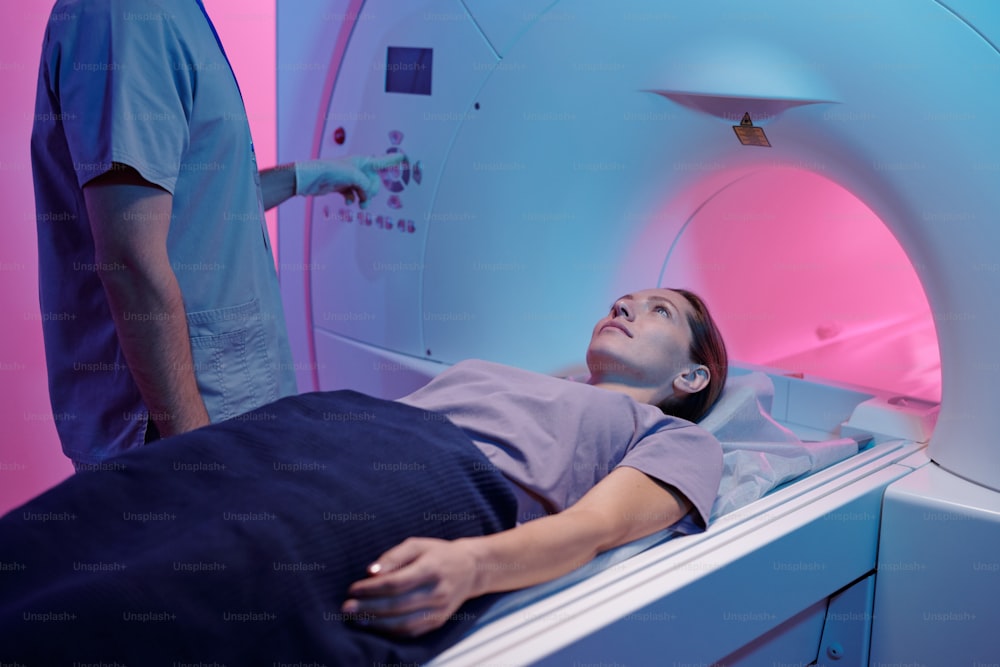 診察のためにMRIスキャン装置に移動する医療台の上の若い女性