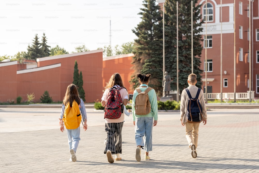 Gruppe zeitgenössischer Schulkinder mit Rucksäcken, die morgens zur Schule gehen