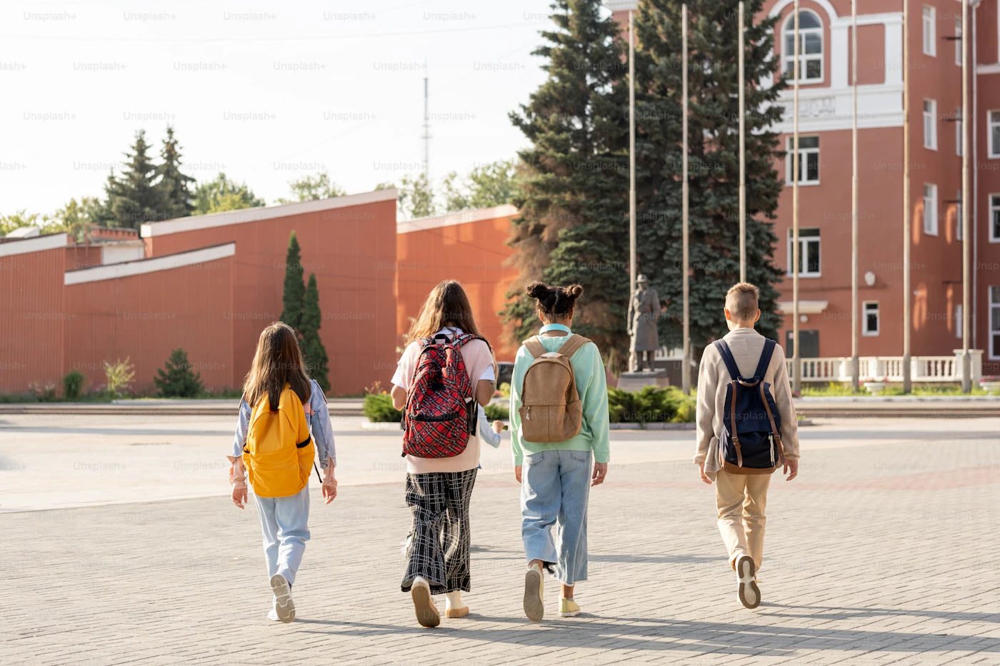 Students wearing backpacks walking toward school